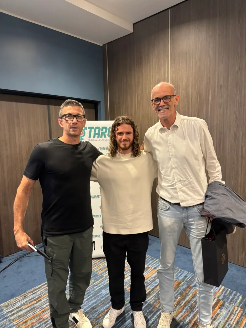 Marks Amosejevs with two football coaches at an event