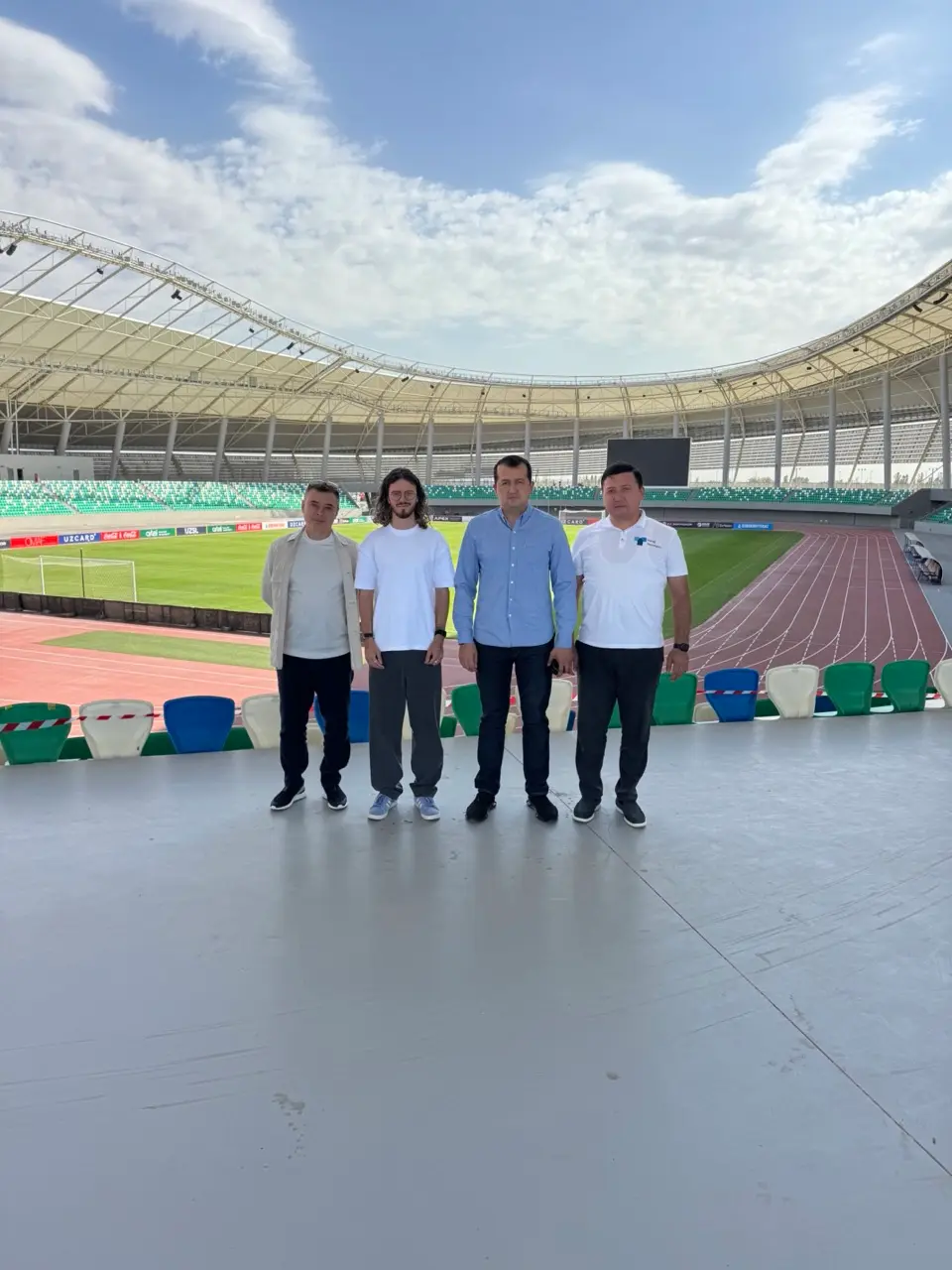 Four men standing in an empty stadium stand
